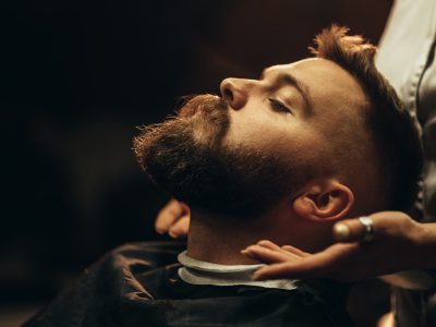 Close shot of a young man beard while he is sitting at a barbershop