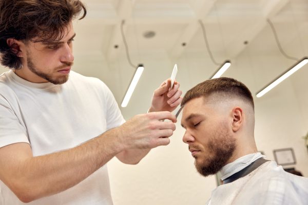 hairdresser does haircut for caucasian bearded man
